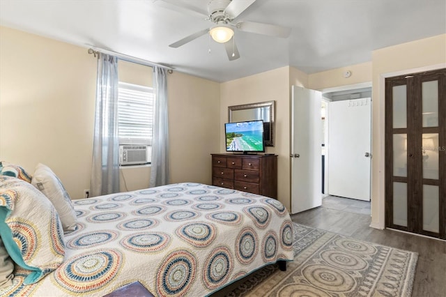 bedroom with cooling unit, ceiling fan, and light hardwood / wood-style floors