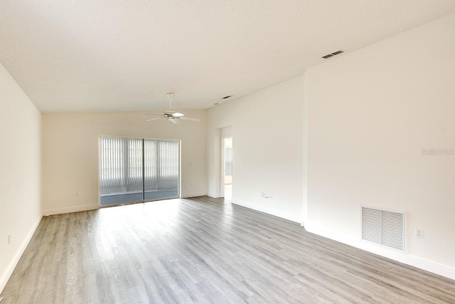 unfurnished room with a ceiling fan, visible vents, vaulted ceiling, and wood finished floors