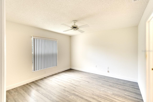 unfurnished room with ceiling fan, a textured ceiling, wood finished floors, and baseboards