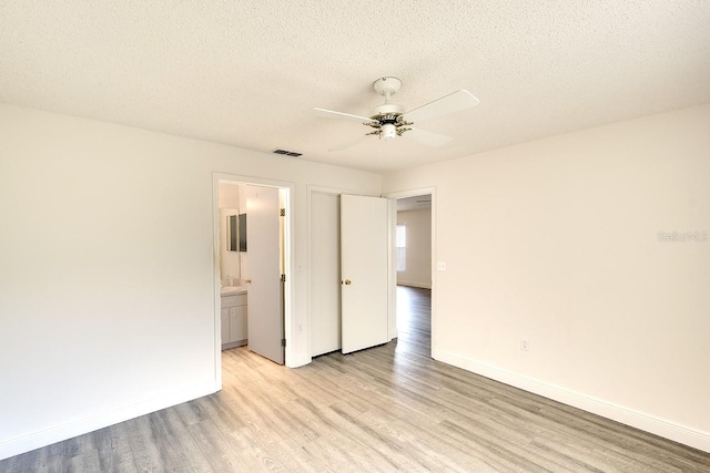 unfurnished bedroom featuring a textured ceiling, light wood-type flooring, visible vents, and baseboards