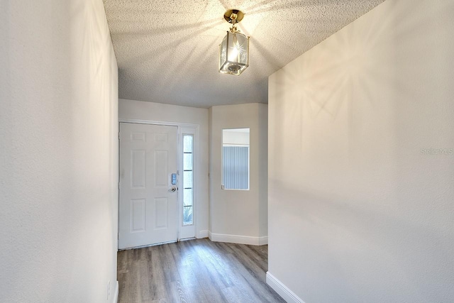 entryway featuring a textured ceiling, wood finished floors, and baseboards