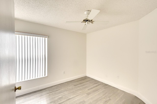 spare room featuring ceiling fan, a textured ceiling, baseboards, and wood finished floors