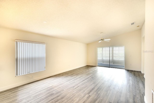 unfurnished room featuring lofted ceiling, wood-type flooring, ceiling fan, and a textured ceiling