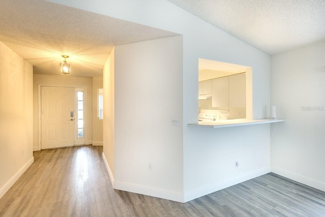 entryway featuring light hardwood / wood-style floors, lofted ceiling, a textured ceiling, and a notable chandelier