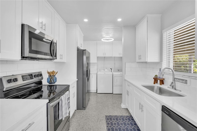 kitchen featuring stainless steel appliances, sink, white cabinets, and washing machine and clothes dryer