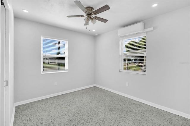 spare room featuring ceiling fan, a wealth of natural light, and an AC wall unit