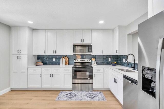 kitchen featuring white cabinetry, appliances with stainless steel finishes, sink, and light wood-type flooring