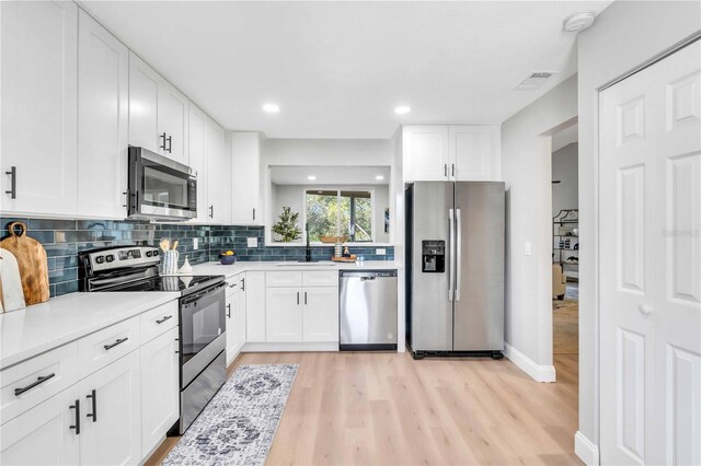 kitchen with white cabinetry, stainless steel appliances, sink, and tasteful backsplash