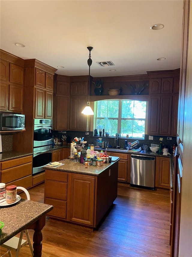 kitchen featuring pendant lighting, sink, stainless steel appliances, dark hardwood / wood-style floors, and a center island