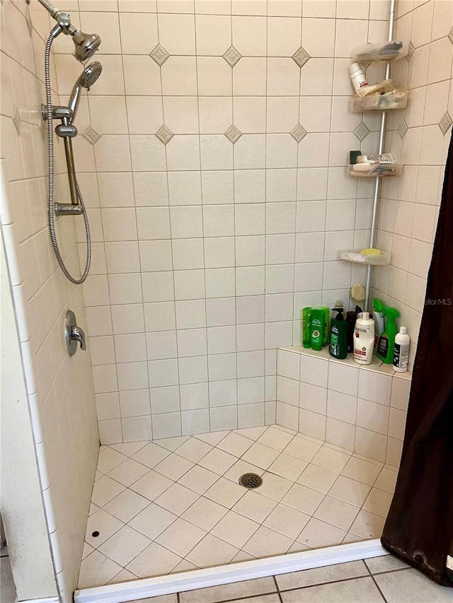 bathroom with a tile shower and tile patterned flooring