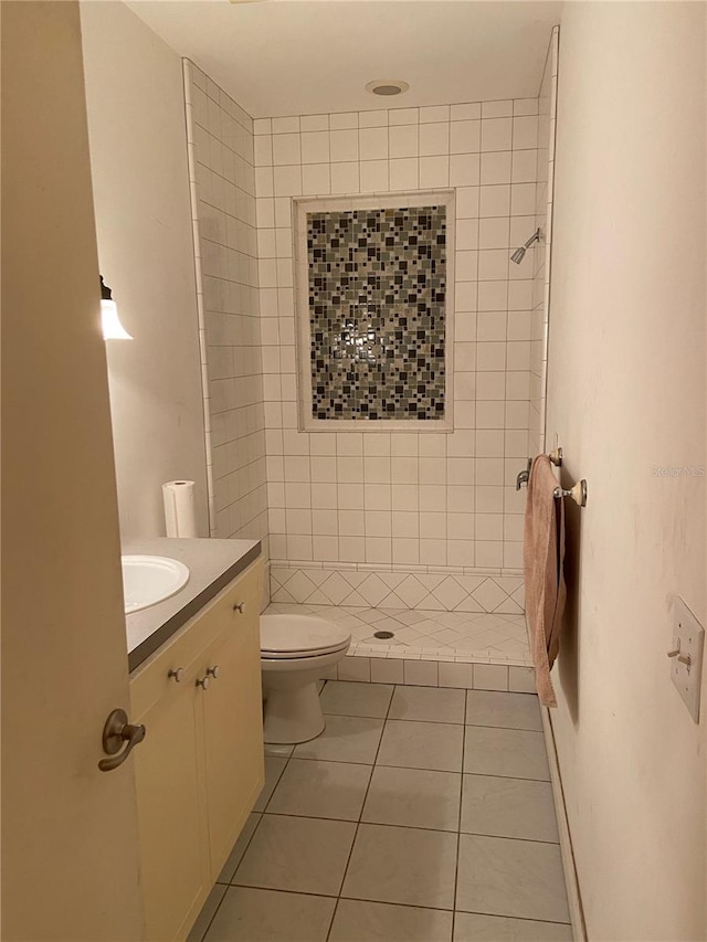 bathroom with a tile shower, vanity, tile patterned flooring, and toilet