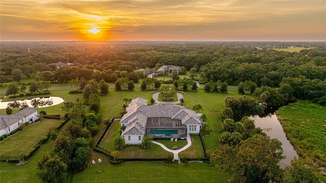 aerial view at dusk featuring a water view