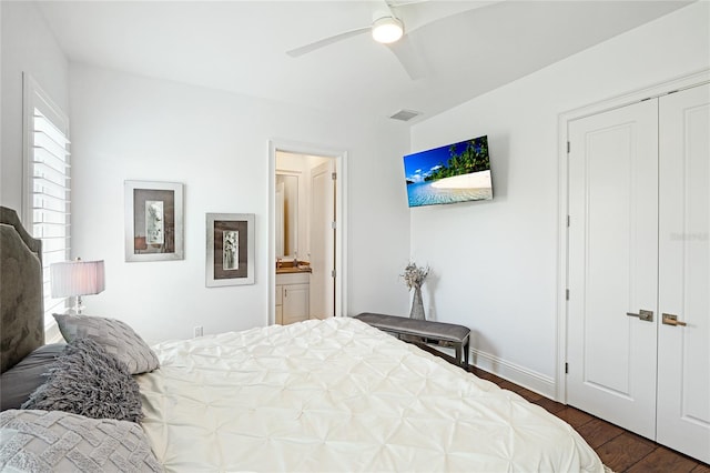 bedroom with ceiling fan, dark wood-type flooring, a closet, and ensuite bath