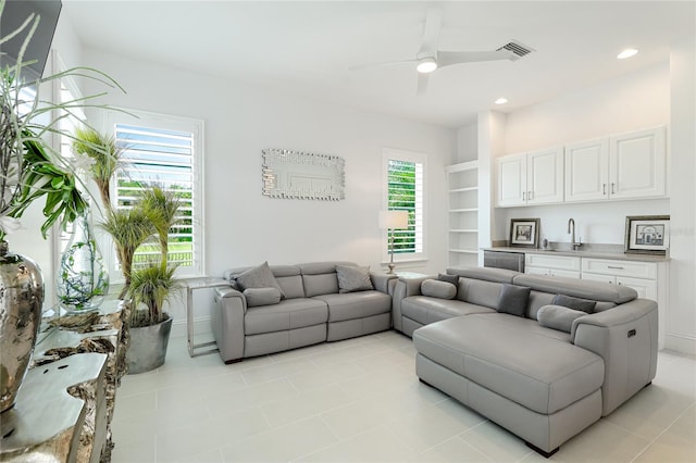 tiled living room with ceiling fan, sink, and built in features