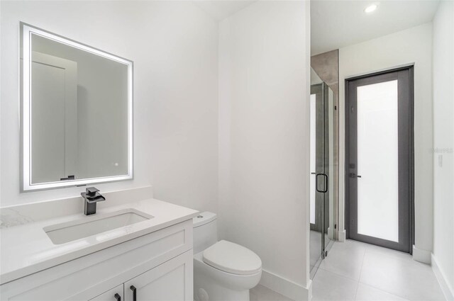 bathroom featuring toilet, tile patterned floors, vanity, and a shower with shower door