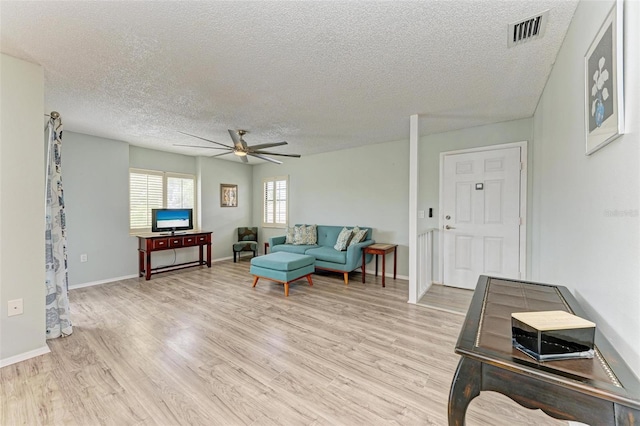 living room featuring a textured ceiling, light hardwood / wood-style flooring, and ceiling fan