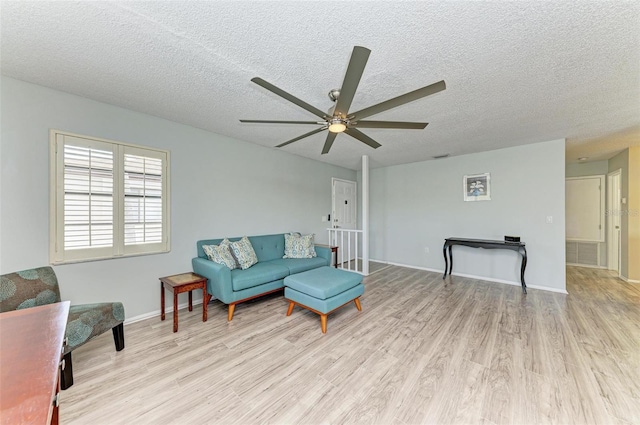 living room featuring a textured ceiling, ceiling fan, and light wood-type flooring