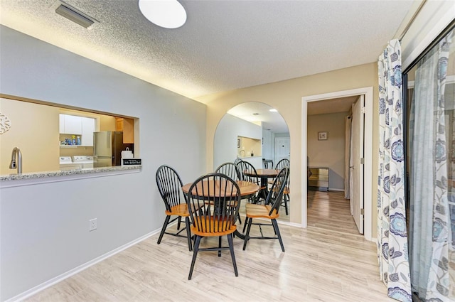 dining room featuring a textured ceiling and light hardwood / wood-style flooring