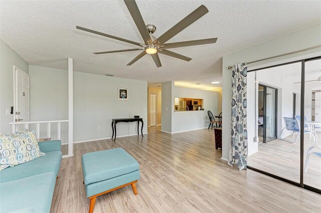 living room featuring light wood-type flooring, ceiling fan, and a textured ceiling