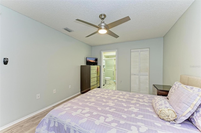 bedroom with a closet, ceiling fan, ensuite bath, light wood-type flooring, and a textured ceiling