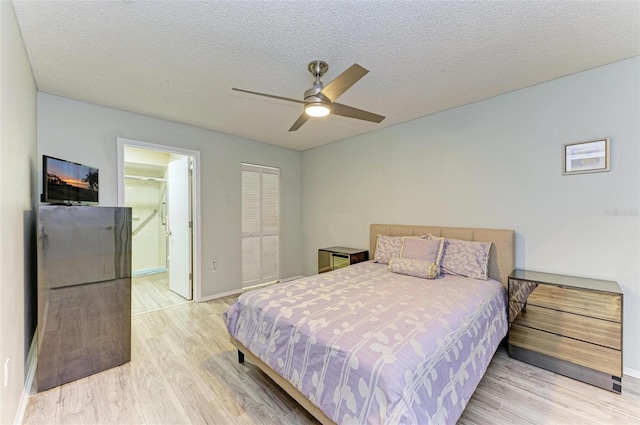 bedroom featuring a textured ceiling, ceiling fan, light hardwood / wood-style floors, a closet, and ensuite bath