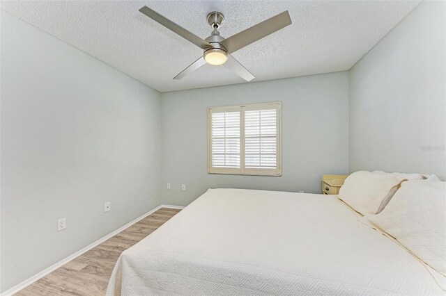 bedroom with light wood-type flooring, ceiling fan, and a textured ceiling