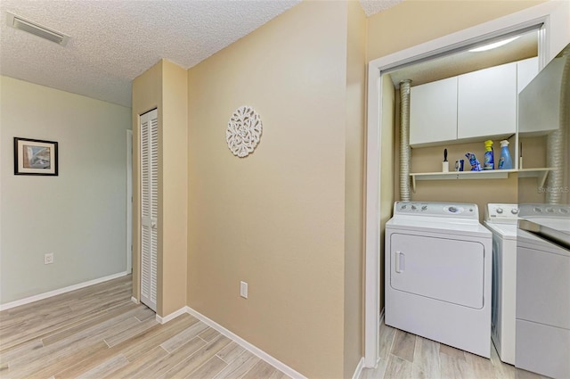 washroom featuring cabinets, a textured ceiling, light hardwood / wood-style flooring, and washer and dryer