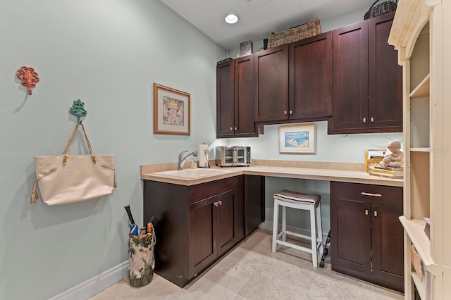 kitchen featuring light tile patterned flooring, dark brown cabinetry, and sink