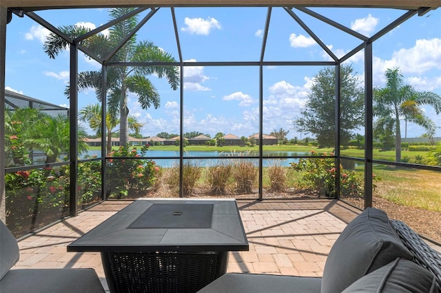 view of patio with a lanai and a water view