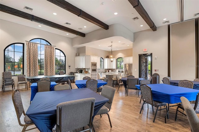 dining space featuring plenty of natural light, beam ceiling, and light hardwood / wood-style floors