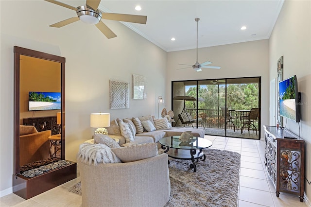 living room with ceiling fan, crown molding, a towering ceiling, and light tile patterned floors