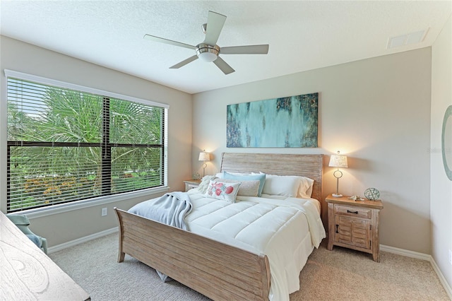 carpeted bedroom featuring ceiling fan and a textured ceiling