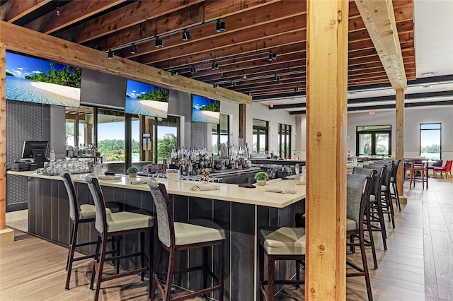 interior space featuring light wood-type flooring, track lighting, and beam ceiling