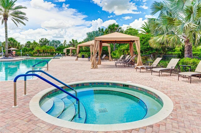 view of pool featuring a patio area, a hot tub, and a gazebo