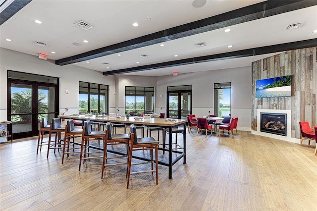 dining space featuring beam ceiling, french doors, plenty of natural light, and a fireplace