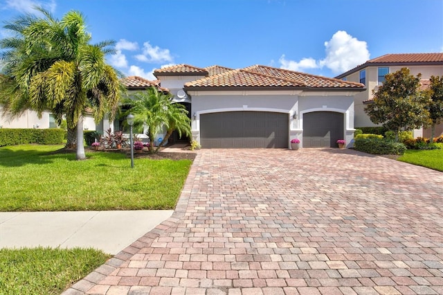 mediterranean / spanish home featuring a front yard and a garage