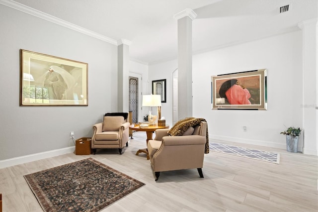 sitting room with crown molding, light wood-type flooring, and ornate columns