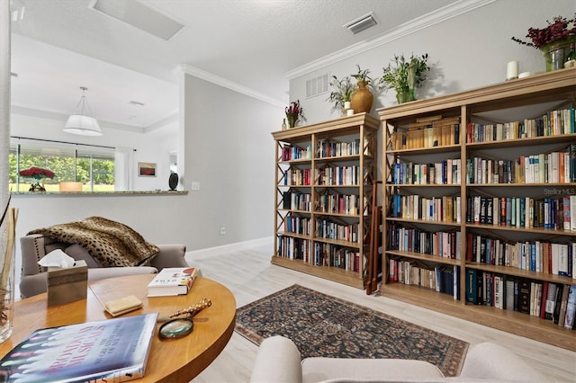 sitting room featuring light wood-type flooring, a textured ceiling, and ornamental molding