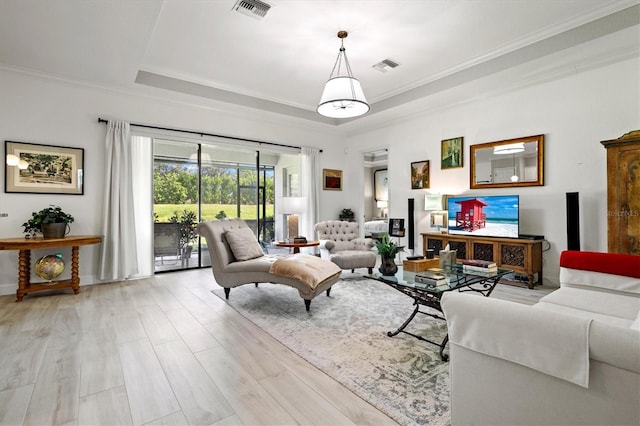 living room featuring crown molding, a raised ceiling, and light hardwood / wood-style flooring