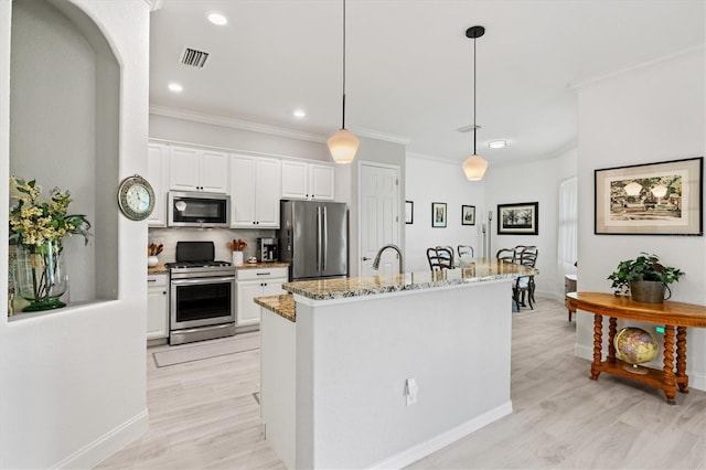 kitchen with ornamental molding, light stone counters, hanging light fixtures, appliances with stainless steel finishes, and white cabinets