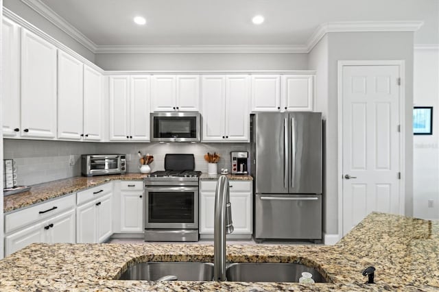 kitchen with stainless steel appliances, ornamental molding, and white cabinets