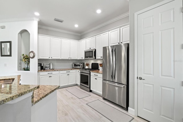 kitchen with crown molding, light wood-type flooring, light stone countertops, stainless steel appliances, and white cabinetry