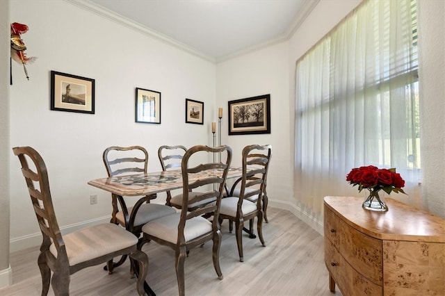 dining space featuring ornamental molding and light hardwood / wood-style flooring