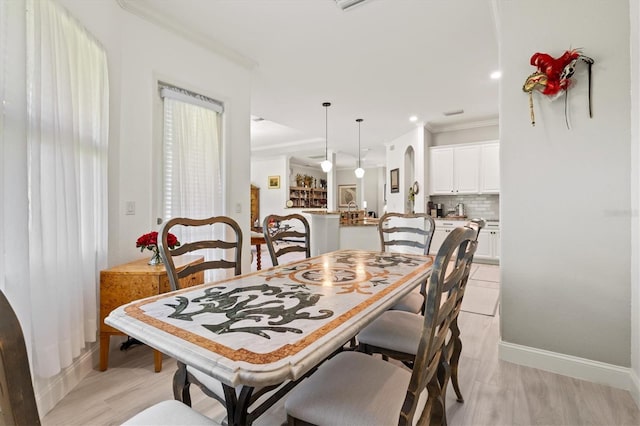 dining space featuring ornamental molding and light hardwood / wood-style flooring