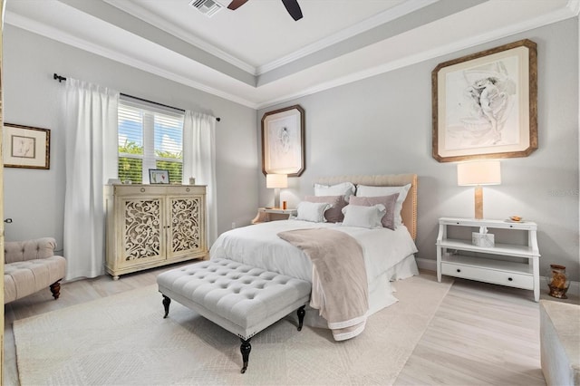 bedroom featuring a tray ceiling, ceiling fan, light hardwood / wood-style floors, and ornamental molding