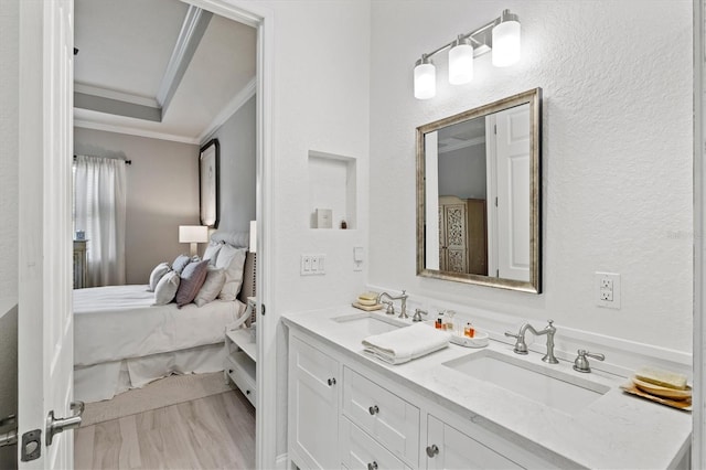 bathroom featuring ornamental molding, vanity, hardwood / wood-style floors, and a tray ceiling