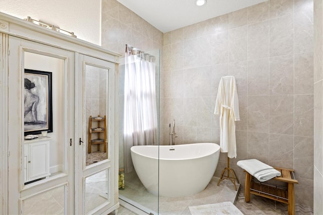 bathroom featuring tile walls, a bath, and tile patterned flooring