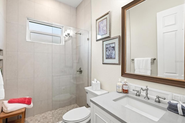 bathroom featuring tiled shower, toilet, and vanity