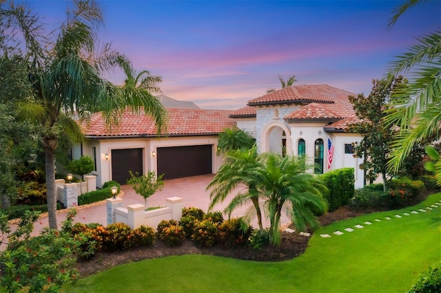 mediterranean / spanish-style house with a lawn and a garage