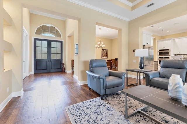 foyer with dark wood-type flooring, a notable chandelier, ornamental molding, french doors, and a towering ceiling